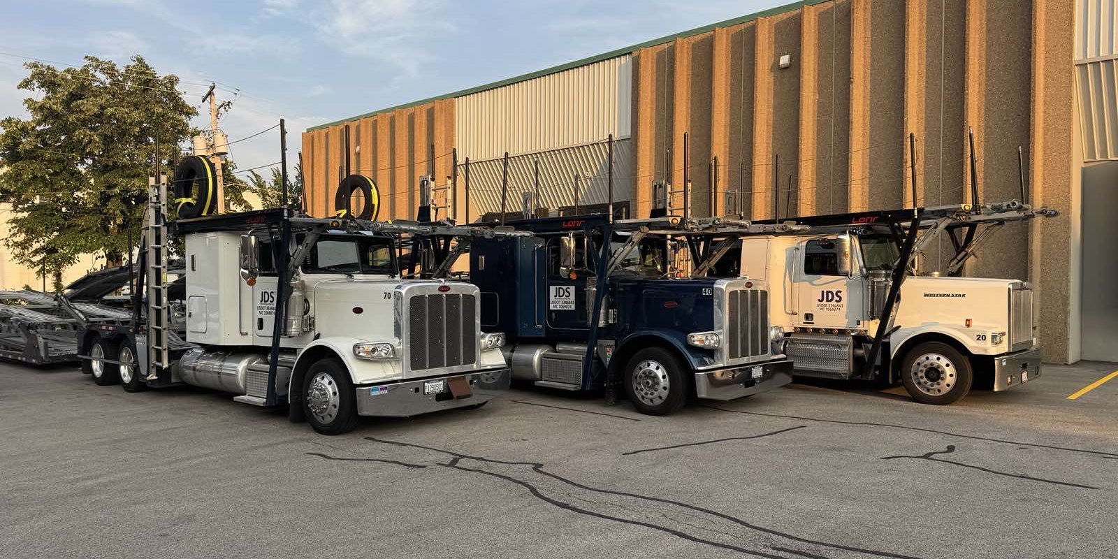 Three JDS car carriers parked side by side at the yard, USDOT and MC numbers on the doors