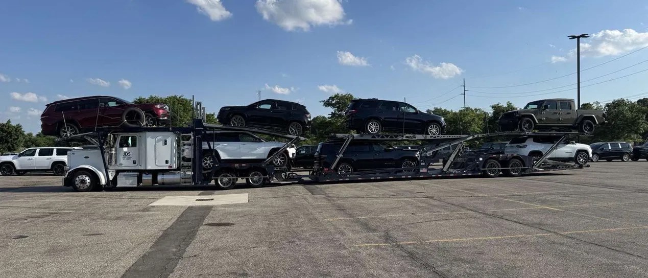 A fully loaded JDS open car carrier on a paved lot