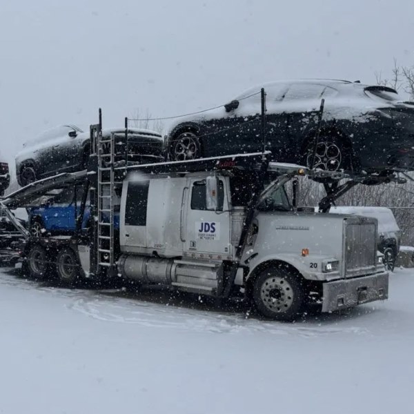 A loaded JDS car carrier on the lot in winter
